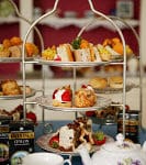 Three-tiered stands topped with snacks, a teapot and teacup and saucer