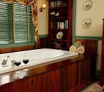 Deep bath tub trimmed in wood with two wine glasses