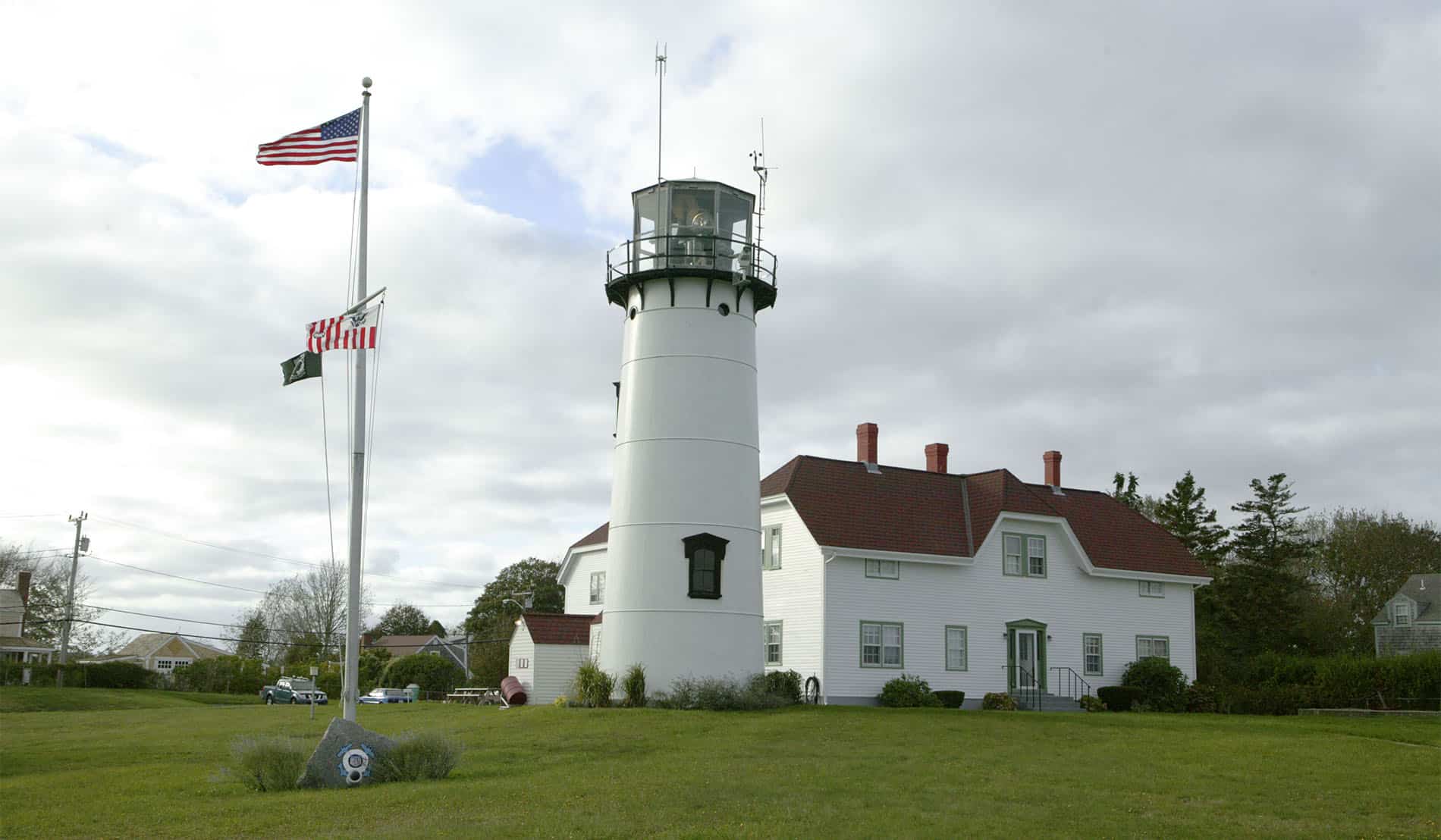 Chatham Lighthouse with sprawling green lawn and American flag in front