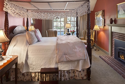 Cape Lady guest room showing rose painted walls and queen canopy bed