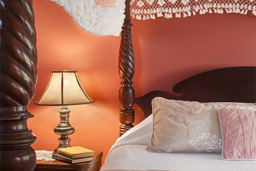 Cape Lady guest room with four poster canopy bed and soft red walls