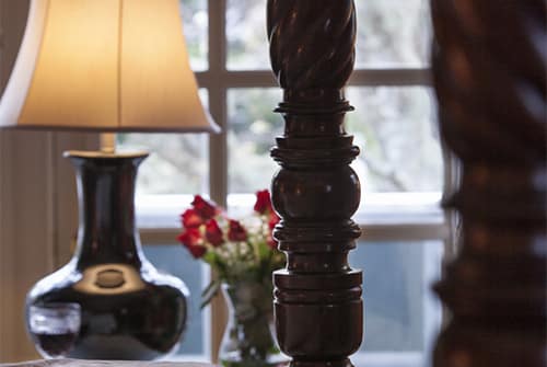 Cape Lady guest room showing carved four poster antique bed with red roses