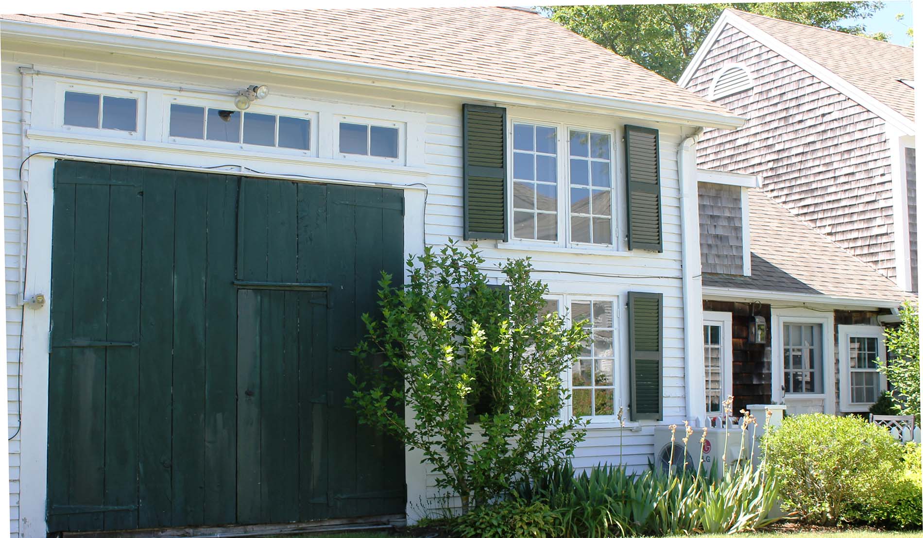 Exterior of Carriage House showing green barn door and gardens