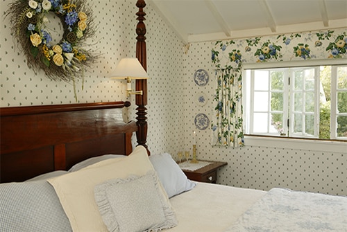 Clarissa Suite bedroom showing king bed with white linens and blue and yellow wallpaper