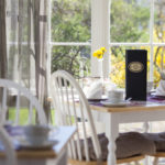 Table in the dining room showing setting for two and bud vase with yellow flowers