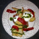 White scrolled plate topped with two slices of eggs Italiano, with red peppers, green sauce and sour cream