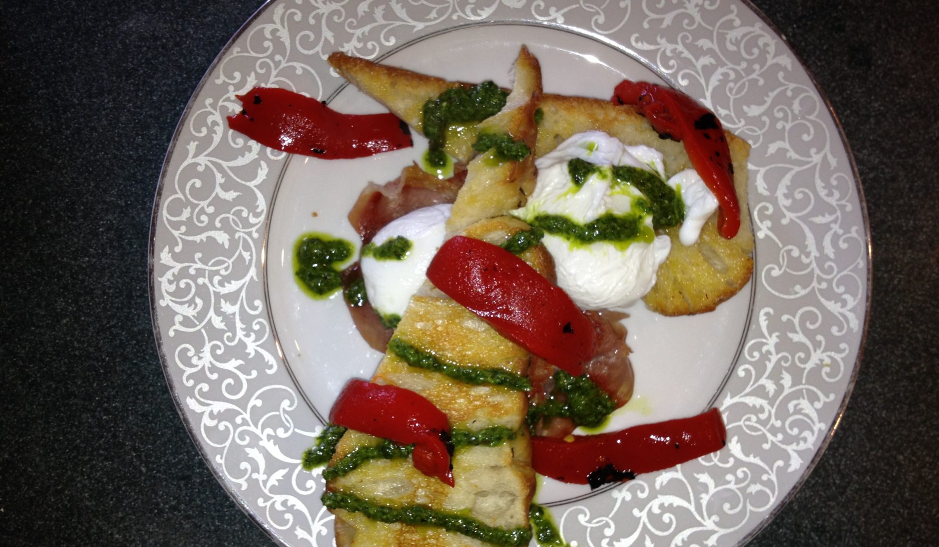 White scrolled plate topped with two slices of eggs Italiano, with red peppers, green sauce and sour cream