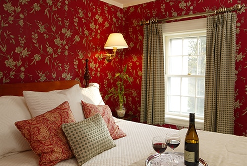 Eliza Jane Suite showing queen bedroom with deep red floral wallpaper and red wine