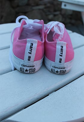 Pair of pink and white Converse tennis shoes on an outside table