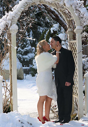 Bride and groom kissing under a snow covered trellis