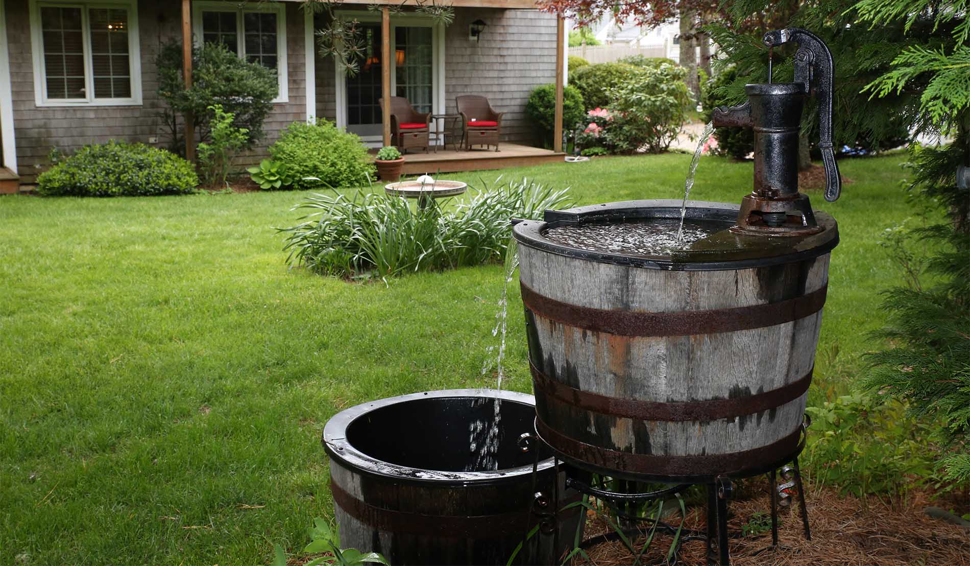 Double bucket fountain behind exterior of stables building showing guestroom patios in background