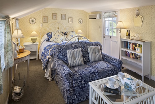 Garden room showing yellow, blue and white color scheme with queen bed and loveseat