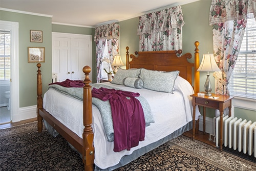 Hannah Rebekah guest room showing floral king bed and burgundy robes