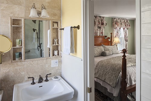 Hannah Rebekah pedestal sink in bathroom looking out to bedroom with floral king bed