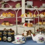 Three, 3-tiered dessert stands topped with lots of baked goodies and flowered teapot with cups and saucers