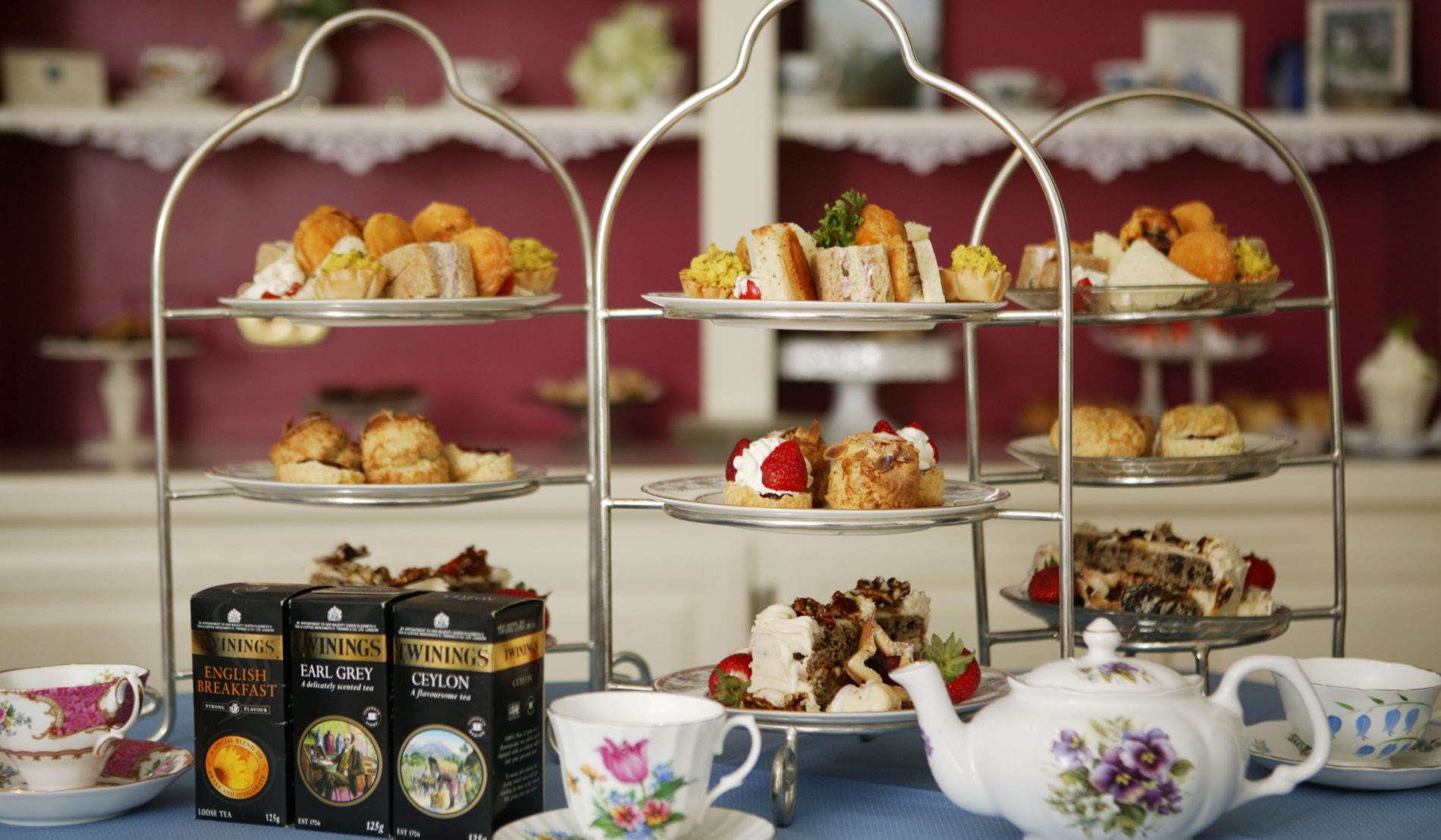 Three, 3-tiered dessert stands topped with lots of baked goodies and flowered teapot with cups and saucers