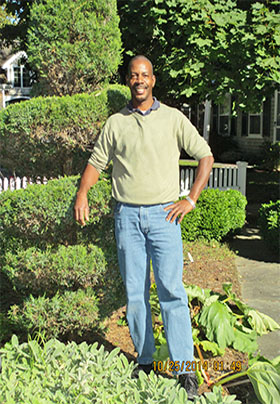 Smiling man standing outside next to manicured landscaping