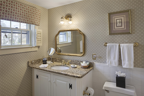 Intrepid bathroom showing marble vanity sink with brass fixtures and window with cornice