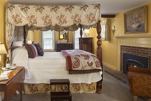 Intrepid guest room showing queen bed with floral and paisley bedding and fireplace