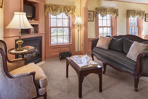 Lady Hope guest room with corner fireplace and TV, several windows and upholstered seating