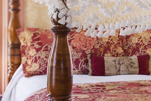 Lady Hope bed showing carved wood canopy bed with pink and red bedding