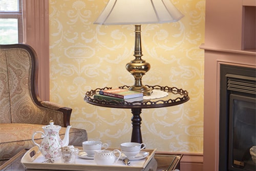 Lady Hope sitting area showing green sofa and accent chair with reading lamp and tea service tray