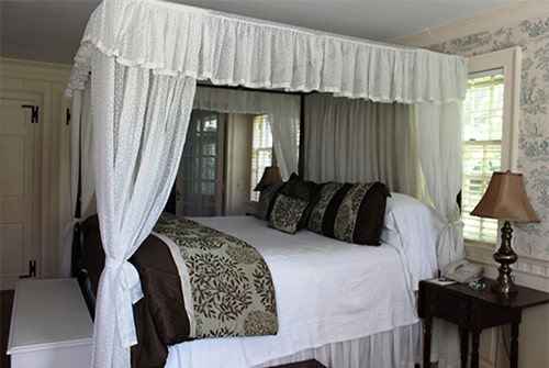 Lady Mariah guest room showing king canopy bed with white bedding and sage green and brown duvet