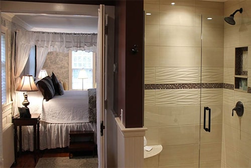 Lady Mariah guest room showing view from bathroom to bedroom with double shower and view of king canopy bed