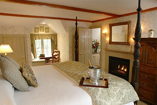 Lydia Harding Suite bedroom showing king bed with sage and beige bedding and champagne and gas fireplace