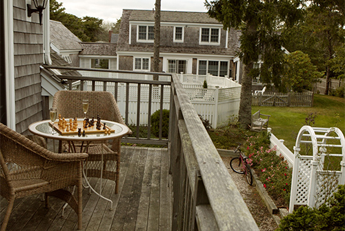 Balcony with wicker chairs and table topped with chess game and champagne flutes