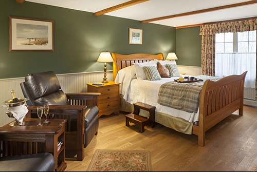 Northern Light guest room showing king sleigh bed, dark green painted walls, and brown leather reclining chairs