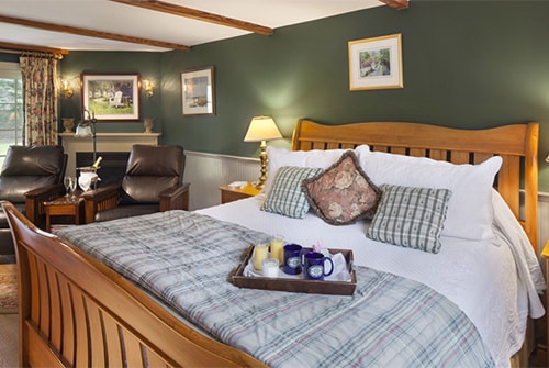 Northern Light guest room showing king sleigh bed, two leather reclining chairs, and sliding glass door leading to private outdoor sitting area