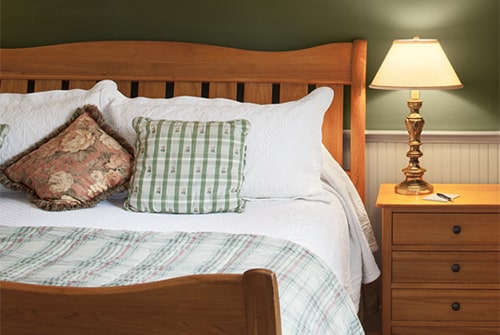 Northern Light guest room showing cherry king sleigh bed and matching night side table