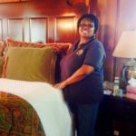 Woman standing next to a nicely made guest room bed