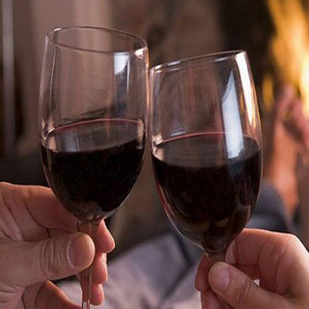 Two people holding wine glasses filled with red wine