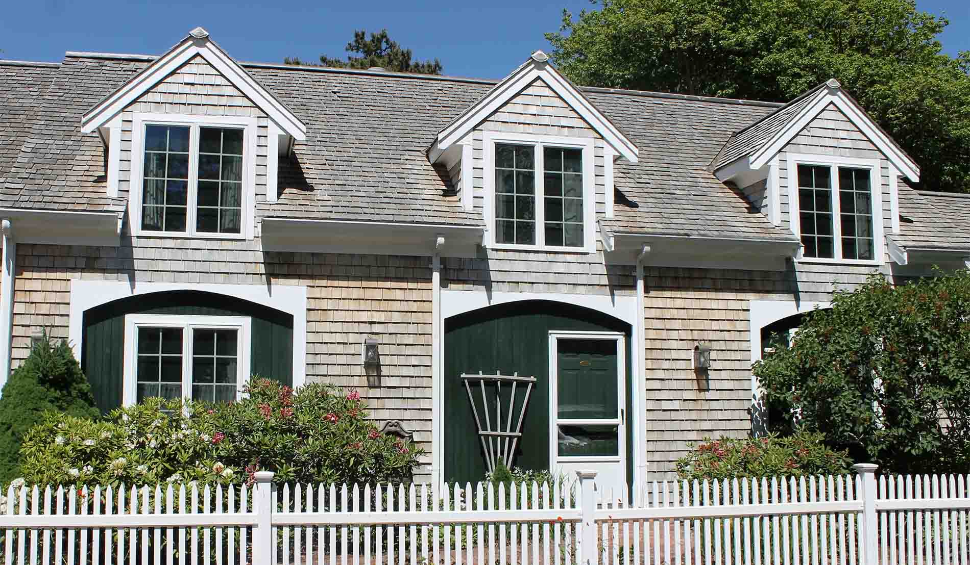 Exterior of stables building showing shingled building with dark green trim and white picket fence