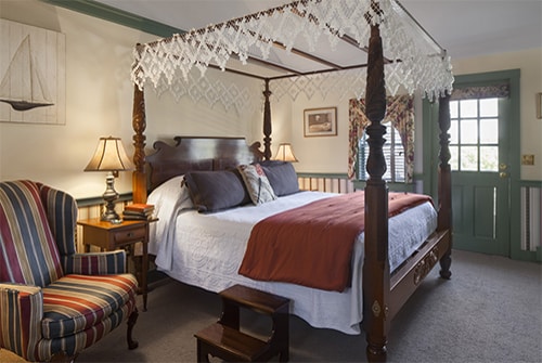 Tradewinds guest room showing burgundy and teal striped wingback chairs and king bed with burgundy bedding