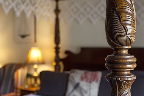 Close up view of carved post on a four poster canopy bed