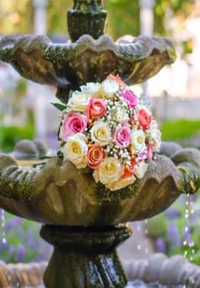 Beautiful pastel bouquet of roses on a tiered water fountain 