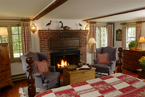 Whirlwind guest room with windows, fireplace, wingback chairs and trunk table