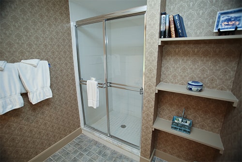 Wild Hunter bathroom showing large stall shower with sliding door and beige paisley wall paper