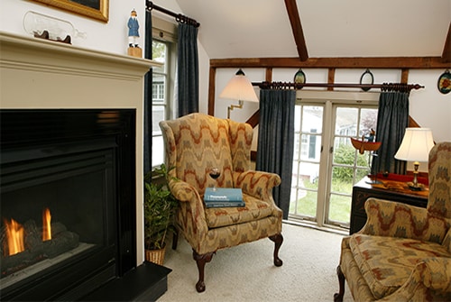 Wild Pigeon guest room showing sunken sitting area with beige wingback reading chairs and gas fireplace