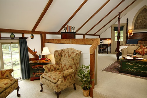 Wild Pigeon guest room showing sunken sitting area with two beige wingback reading chairs and small corner desk