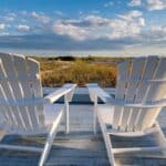 Two white deck chairs looking out at the Cape Cod sand dunes.