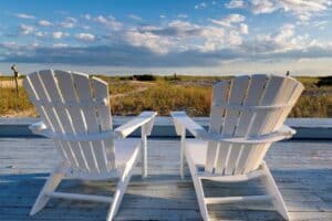 Two white deck chairs looking out at the Cape Cod sand dunes.