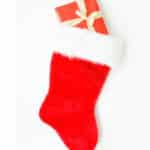 Red present with white bow sticking out of a red stocking with white trim