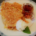 White and blue plate topped with homemade French toast, a dallop of butter, and small glass of syrup