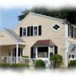 Beige sided two-story building with black shutters and white fence